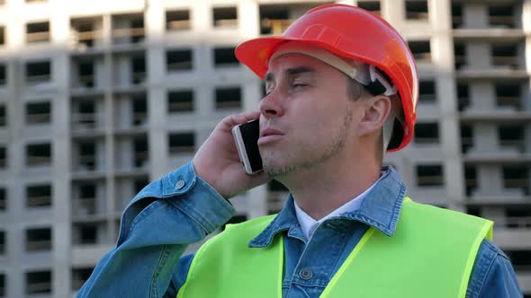 Worker Staff in Protective Helmet Using Smartphone at Construction Site
