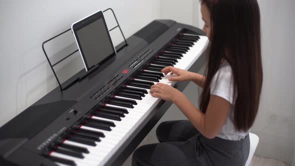 A Little Girl Learns to Play the Piano From Video Lessons