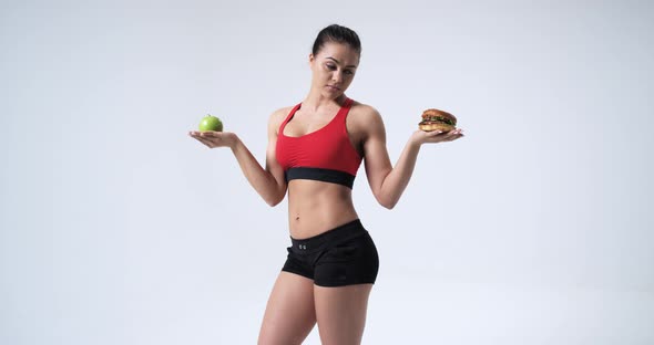 Athlete Woman Choosing Between Apple and Hamburger