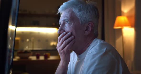 Close Up of Disappointed Aged Man Watching Tv News Sitting Near Screen