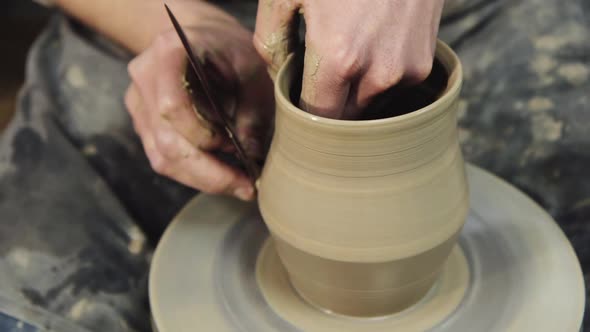 The Hands of a Potter Make a Jug on a Potter's Wheel