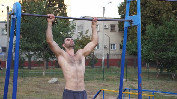 Young Sportsman Doing Pull Ups at Sports Ground