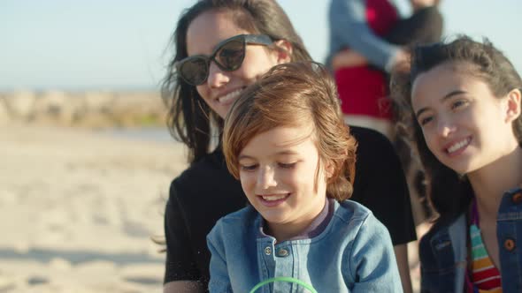 Medium Shot of Happy Brother Sitting on Sisters Knees on Beach