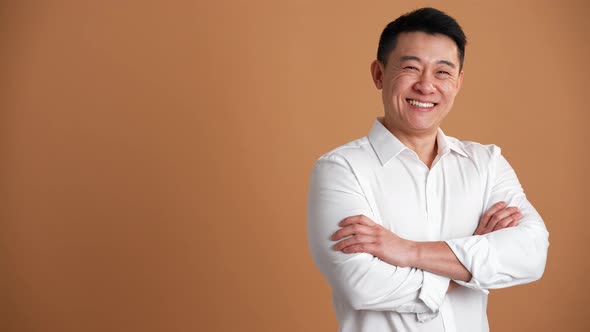 Smiling asian businessman turning to camera with crossed arms