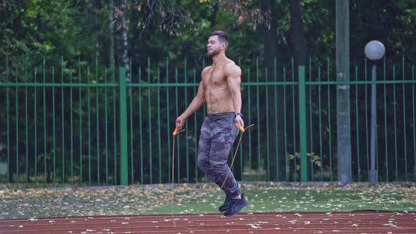 Man exercising with jumping rope. Yong handsome fit man jumping rope on stadium