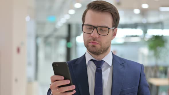 Businessman Browsing Internet on Smartphone at Work