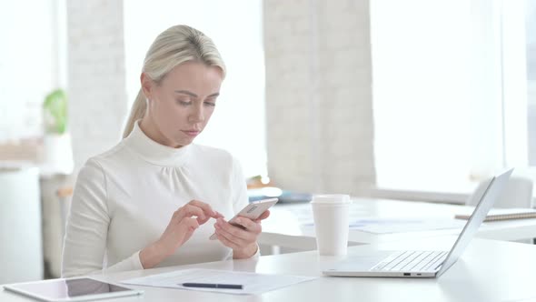Disappointed Young Businesswoman Using Smartphone in Office