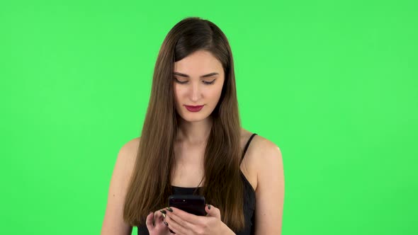 Young Smiling Woman Texting on Her Phone. Green Screen