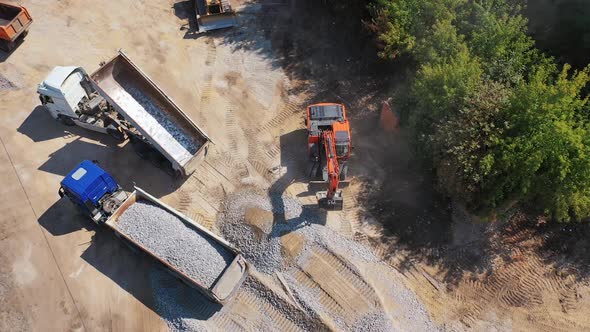 View from above on excavator and two trucks. Excavator working near the machinery
