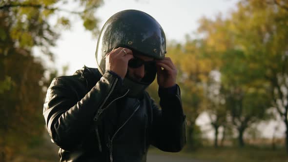 A Young Man in Black Leather Jacket and Helmet Wearing Sunglasses While Sitting on His Motorcycle