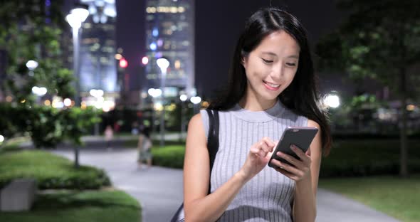 Woman using mobile phone in city at night 