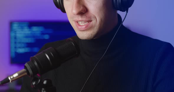 Closeup of Male Blogger in Headphones Talking in Microphone Recording Podcast in Studio
