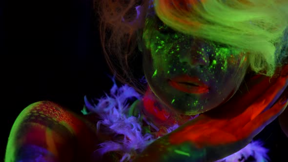 Beautiful Lady with Bright Makeup with Fluorescent Paints Ultraviolet Light on Face of Model Orange