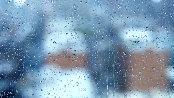 Rain Drops Pouring Down On Glass Window on Cold Raining Day