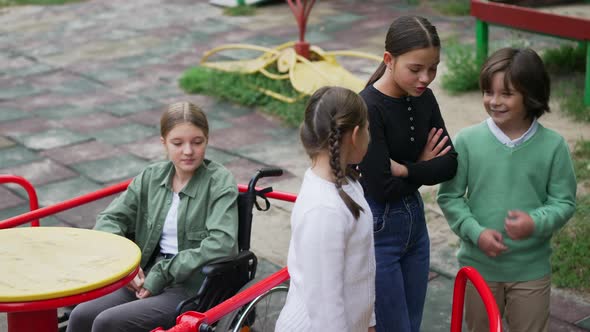 Group of Friends Talking Ignoring Disabled Sad Girl in Wheelchair on Playground