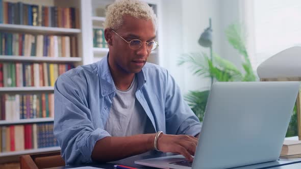 Ethnic African American Man Freelancer Works with Laptop in Coworking Offices