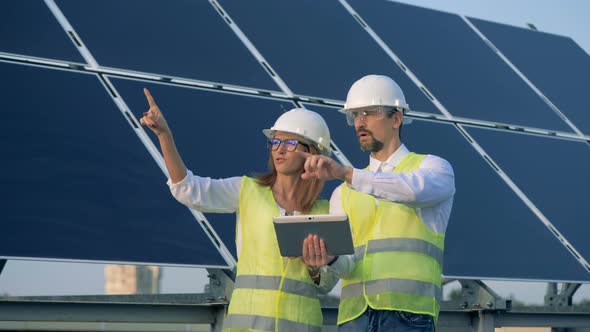 Construction Employees in the Process of Discussion and Planning While Standing Beside a Solar Panel