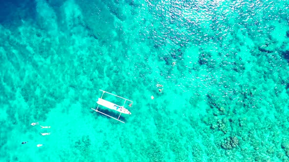 Wide angle overhead tourism shot of a white sandy paradise beach and blue water background in colour