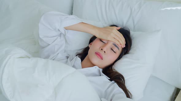 Attractive sleep young woman touching forehead, feeling bad with fever and headache after wake up.