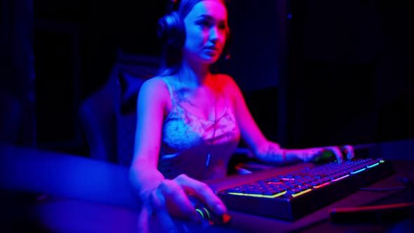 Tattooed Young Woman Playing Game in Neon Gaming Club