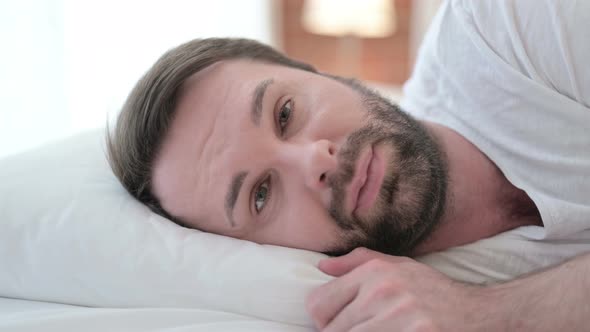 Close Up of Serious Beard Young Man Looking at Camera in Bed
