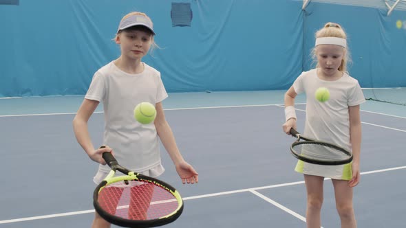 Girls Practicing Tennis Ball Hitting On Racket