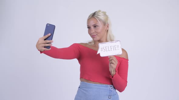 Happy Young Beautiful Blonde Woman Taking Selfie with Paper Sign