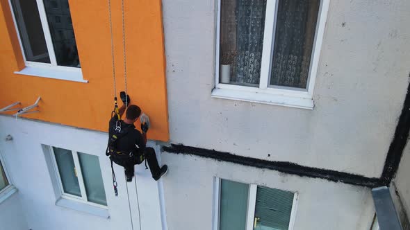 Painting and Decorating Buildings. Worker on a Construction Site of a High-rise Building. Dangerous