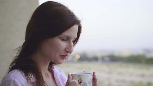 Young Woman Drinks Tea at a Balcony