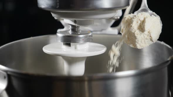 Close-up Shot of Chef Pouring Flour From Spoon Into Electric Mixer Bowl. Slow Motion. Preparation of