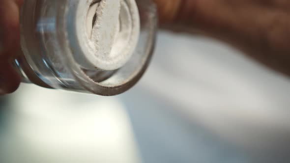 Macro shot: the chef is using a salt mill to add some salt to his food, salt is falling