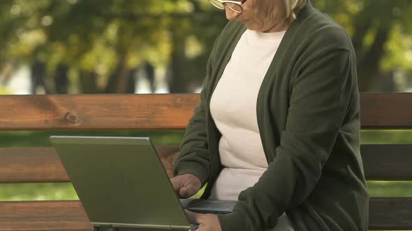 Aged Female Typing Laptop Keyboard, Sitting on Bench, Internet Search, App