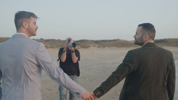 Photographer taking pictures of gay couple before their wedding on the beach