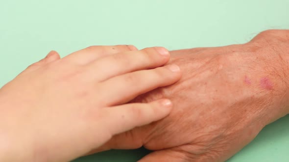Friendship and support for grandson and grandfather theme. Close-up of a kid's hand stroking his gra