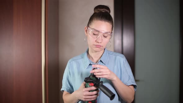 A young girl puts on safety glasses and inserts a drill into the drill