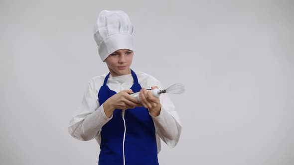 Cheerful Little Cook Having Fun Imitating Shooting with Electric Hand Blender Posing at White