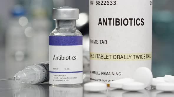 Antibiotics in vial and pills in lab with syringe