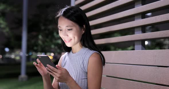 Woman using smart phone in city at night 