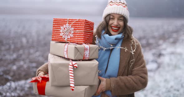 Portrait of a Happy Woman with Gift Boxes on the Snowy Field