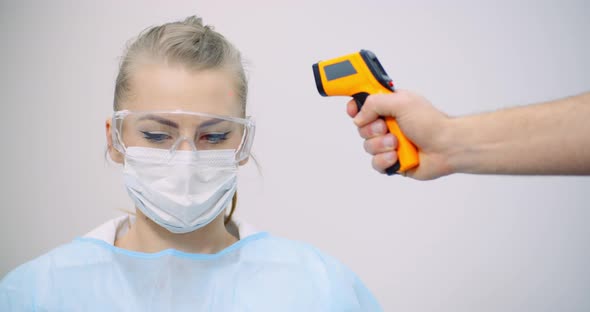 Doctor Measuring Patient Temperature at Health Care Clinic