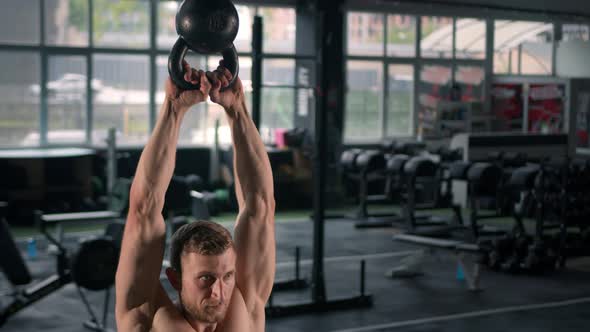 Young male athlete trains in the gym with dumbbells, crossfit, endurance training