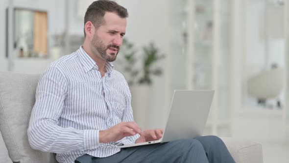 Young Man with Back Pain Using Laptop at Home