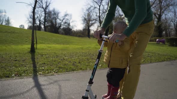 Adorable infant son riding on scooter in public playground, Zagreb, Croatia.