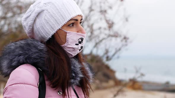 A woman with long dark hair in a mask from air pollution and the Covid19 coronavirus walk