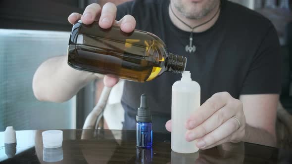 Man Is Mixing Liquid or E-liquid in Bottle for E-cig or Electronic Cigarettes
