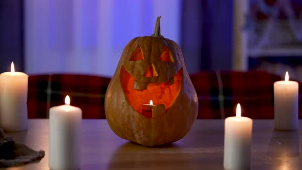 Traditional Halloween Pumpkin with Carved Smiling Face Glows on the Table in the Dark