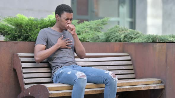 Sick Young Young African Man Coughing on Bench Outdoor