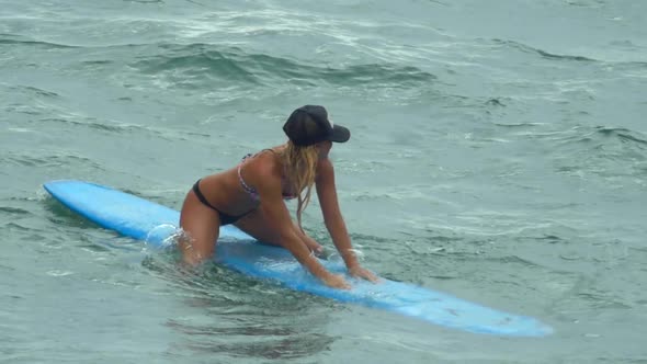 A young woman surfing in a bikini on a longboard surfboard.