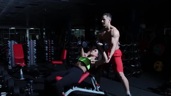 Gym Training  Woman Pumping Her Hands Muscles with a Trainer Helping Her