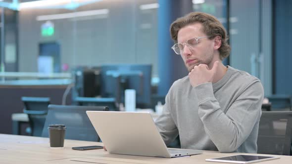 Young Businessman with Laptop Taking Nap in Office